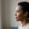Soft profile portrait of a calm adult in early morning light against a neutral interior, conveying introspection and the early steps of trauma recovery