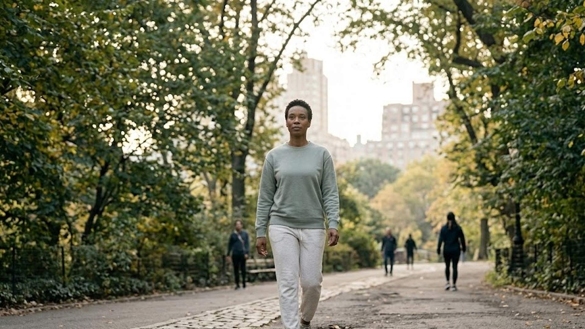 Adult walking in a quiet Manhattan park in soft morning light, taking a deliberate daily walk as part of a resilience-building routine