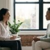 Therapist and adult client in a calm office setting in midtown Manhattan, sitting in conversation in soft natural light during structured trauma-focused therapy