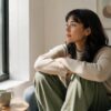 A person sitting calmly by a window in soft natural light, reflecting quietly