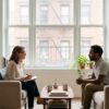 Clinician and client in conversation in a bright living room with plants and soft neutral furnishings